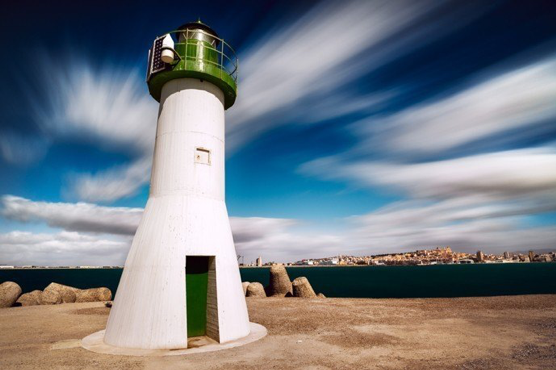 lighthouse green white blue sky clouds blur slow shutter speed