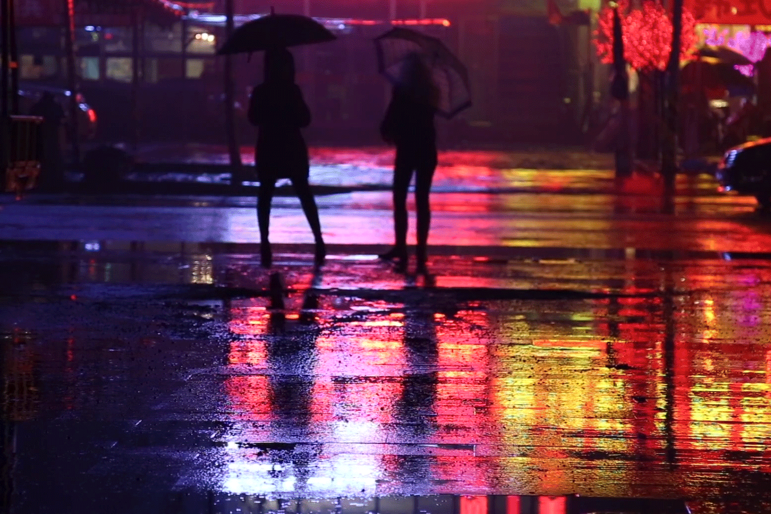 cinemagraph moving image people rain lights puddles neon night umbrella figures city