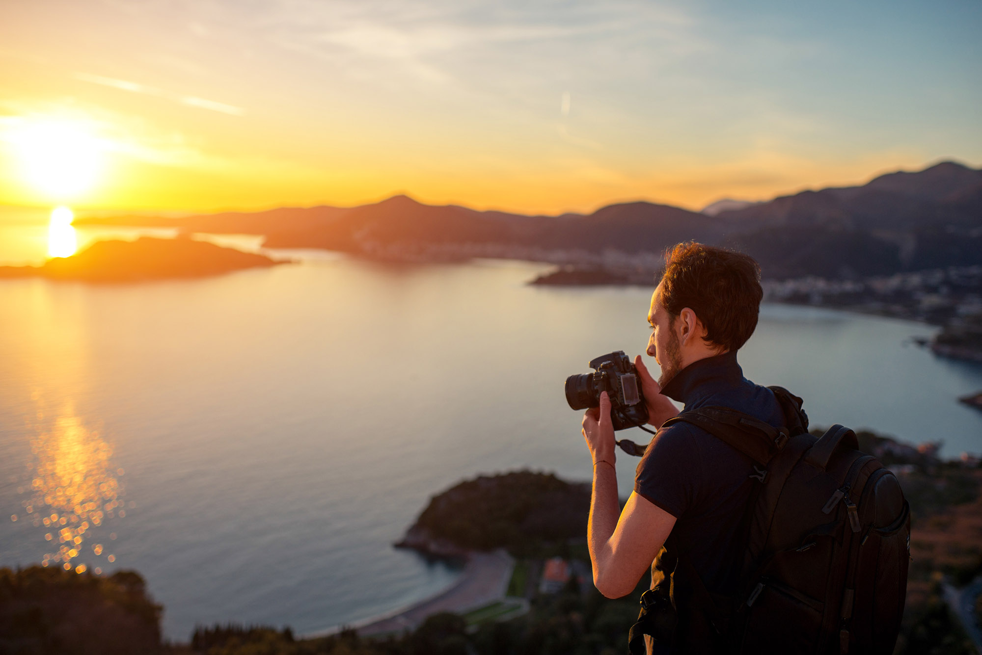 man camera cliff top sunset polo shirt wind taking photographs of landscape