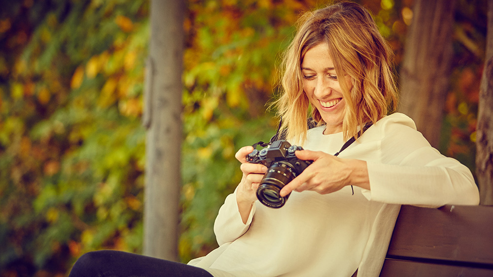 smiling photographer looking at camera on bench